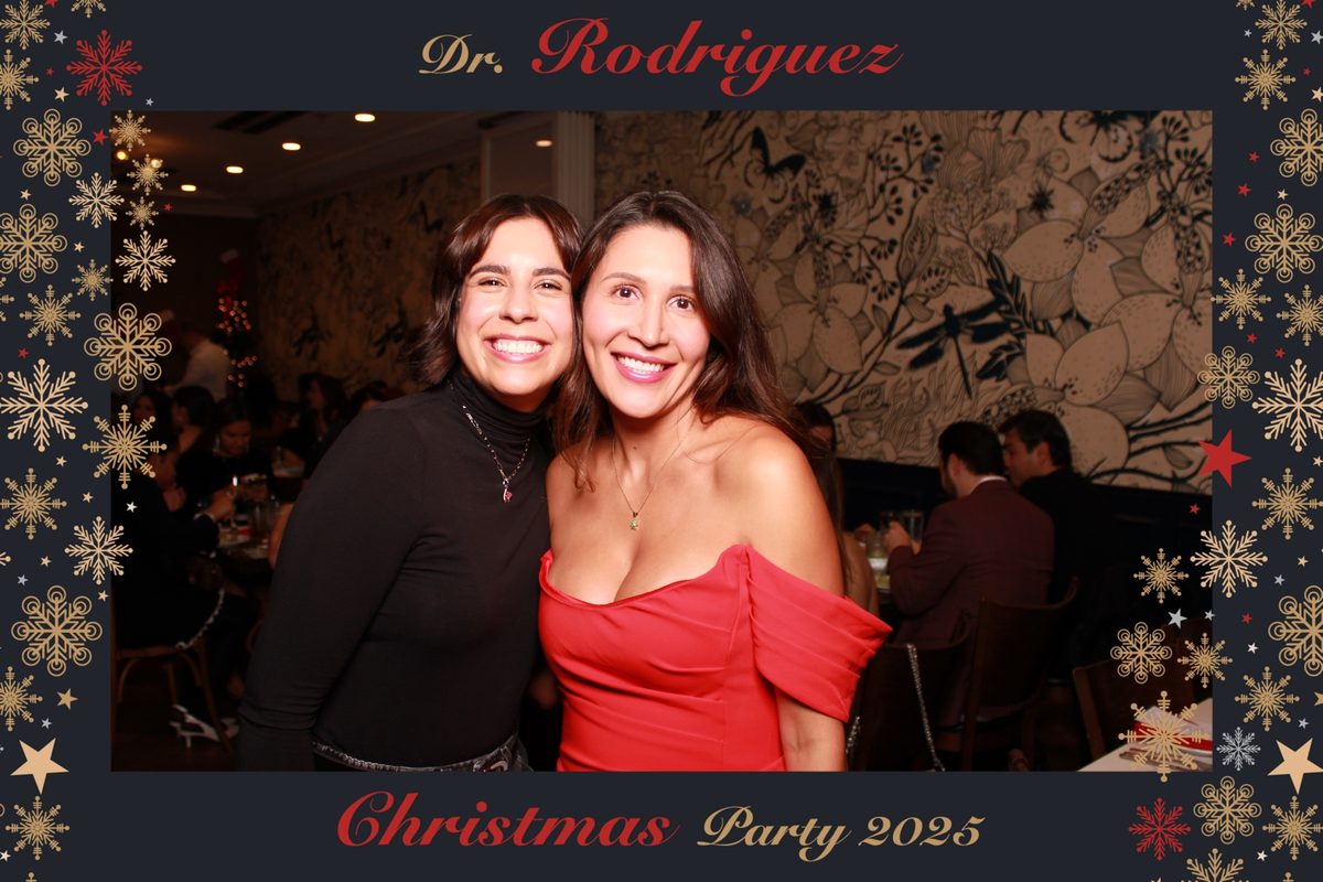 Two guests smiling at a Christmas party photo booth